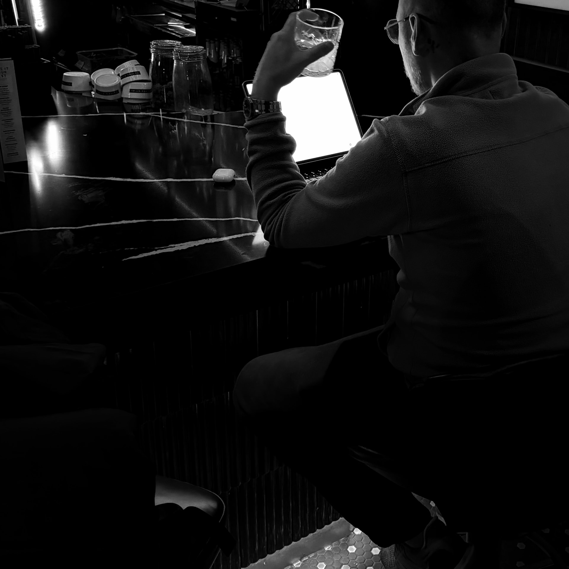 Rob Adshead building a project on his MacBook at a bar, in black and white